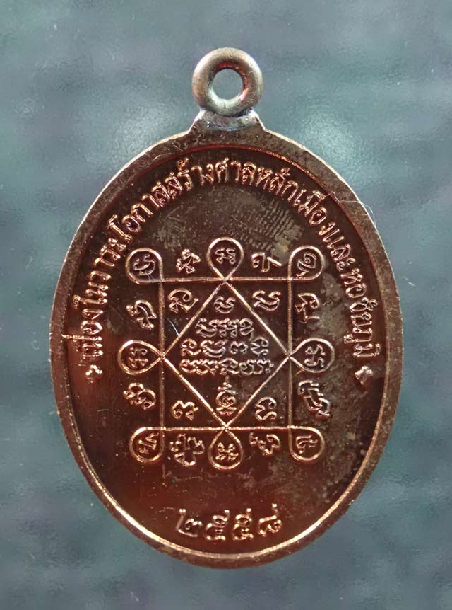 เหรียญห่วงเชื่อม (รุ่นแรก) หลวงพ่อทอง (วัดบ้านไร่ นครราชสีมา) วัดพระพุทธบาทเขายายหอม จ.ชัยภูมิ รุ่นประวัติศาสตร์ไตรภาคี สร้างศาลหลักเมืองและหอชัยภูมิ ปี 2558 เนื้อทองแดงผิวไฟ หมายเลข ๗๖๕๓ ขนาดพระสูง 4 ซ.ม. พร้อมกล่องเดิม