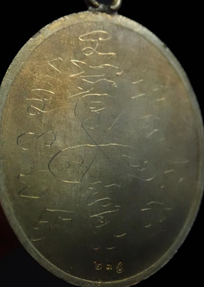 เหรียญปั้มกระบอกห่วงเชื่อมโบราณ รุ่นชาตรีเก้ายอด หลวงพ่อสำเริง นริสสโร วัดบ้านตะกวน จ.ศรีสะเกษ เนื้ออัลปาก้าหลังเรียบจารมือ (เหรียญอยู่ในชุดกองบุญร่วมสร้าง) หมายเลข 23